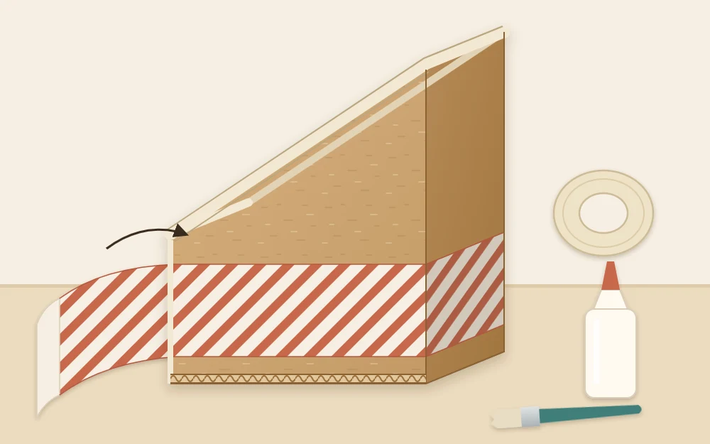 Cut magazine holder with sloped edges bound in paper tape and a strip of patterned paper being wrapped around the outside
