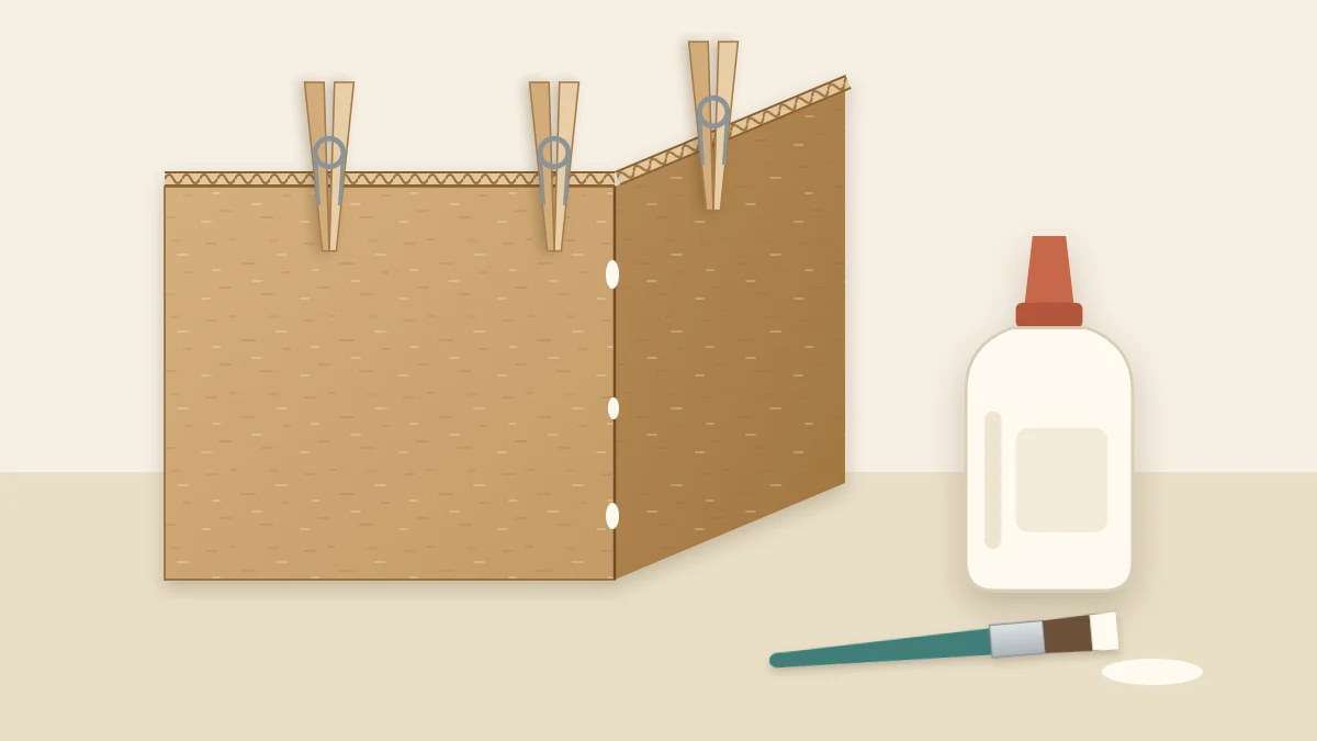 Two cardboard panels joined at a right angle and held with clothespins, with a bottle of white glue and a small brush